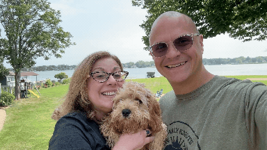 Gif of Julie and Brett outside, holding Charlie the cavapoo dog. Julie is waving.