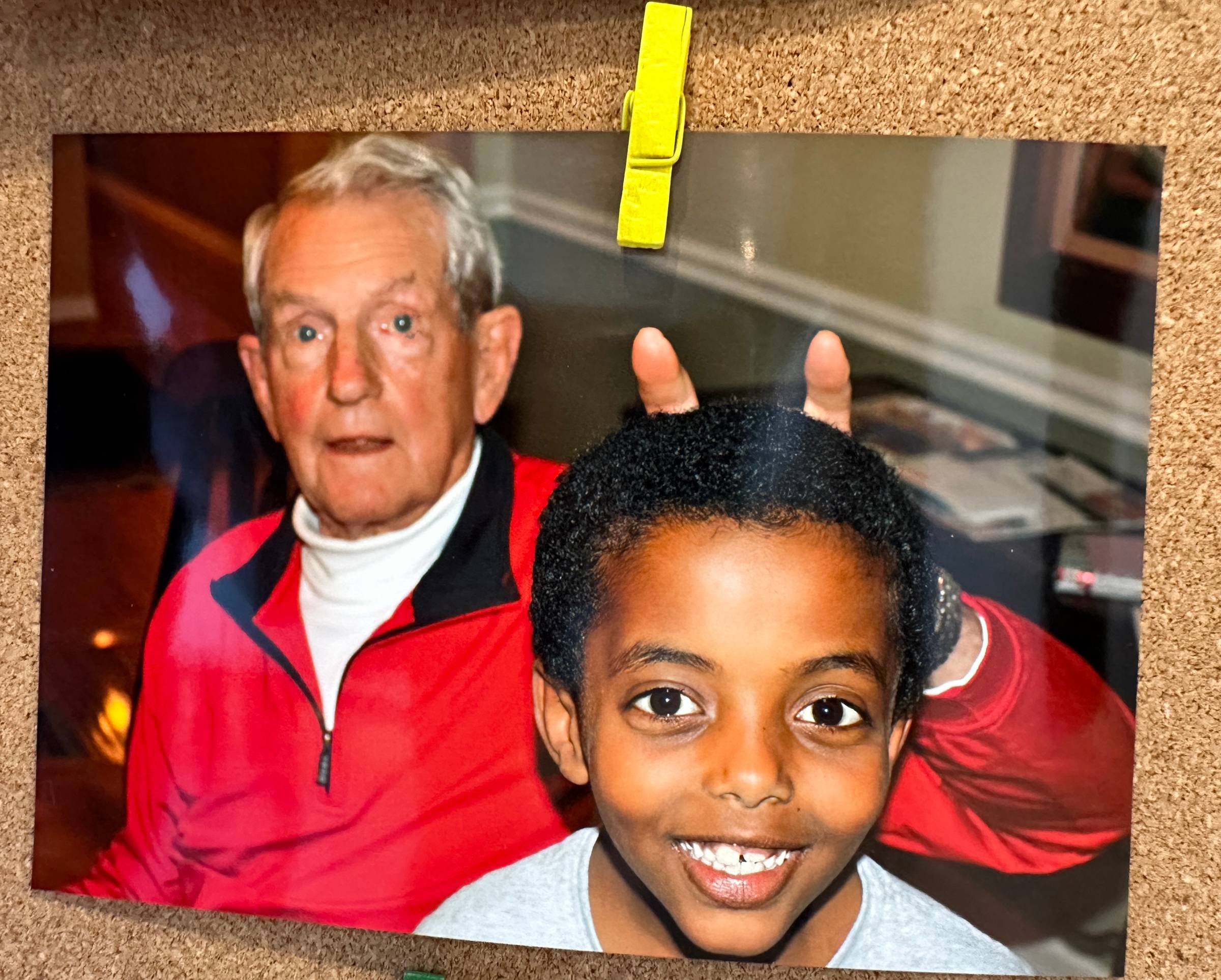 photo of an elder man with two fingers held up behind the head of his grandson