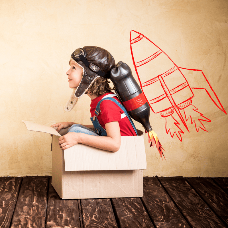 a child sitting in a cardboard box pretending to be in a spaceship