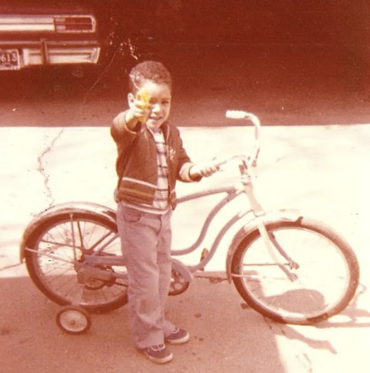 boy standing beside a bike with training wheels
