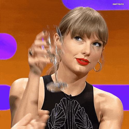 GIF of Taylor Swift raising a glass of wine in cheers.