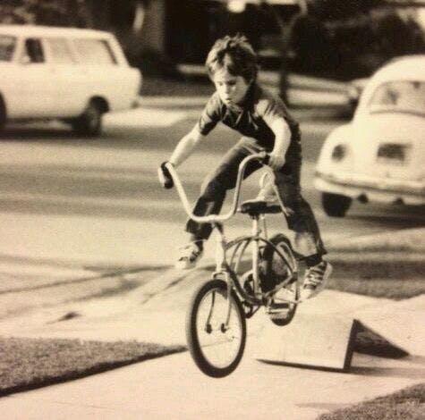 a boy jumping off of a ramp on his bike