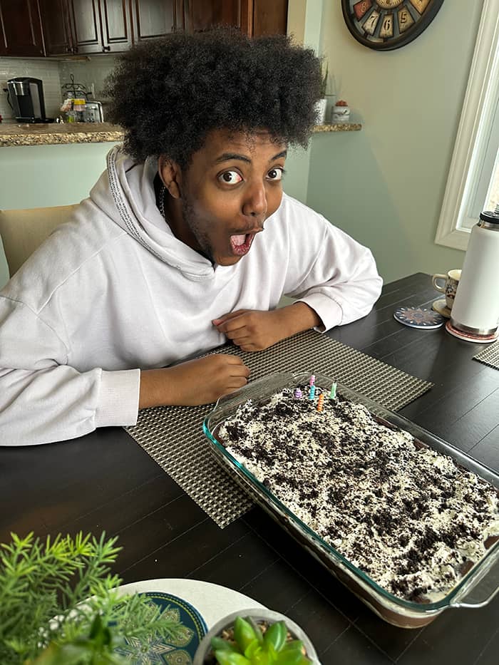 a photo of 20-year-old Mickey making a silly "surprised" face, sitting at the table in front of his birthday dessert.