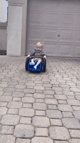a toddler grinning while trying out his wheelchair