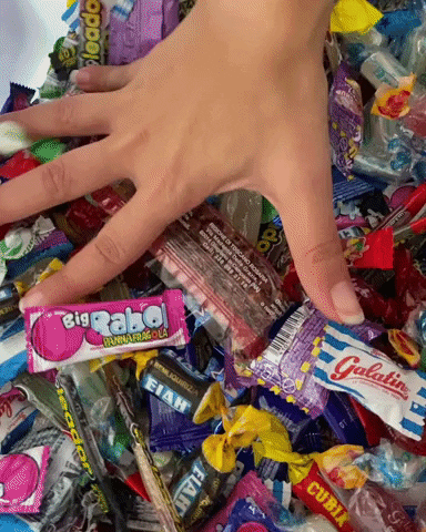 gif of a woman running her hands through a big bowl of candy