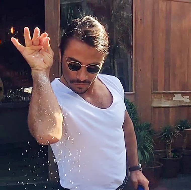 Nusret Gökçe aka Salt Bae sprinkling salt and wearing sunglasses and a white t-shirt