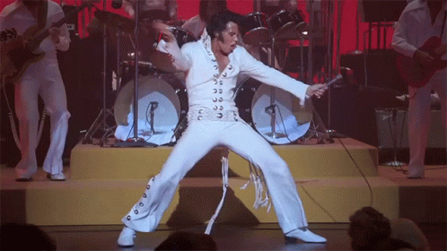 Elvis in a white suit doing a signature dance move