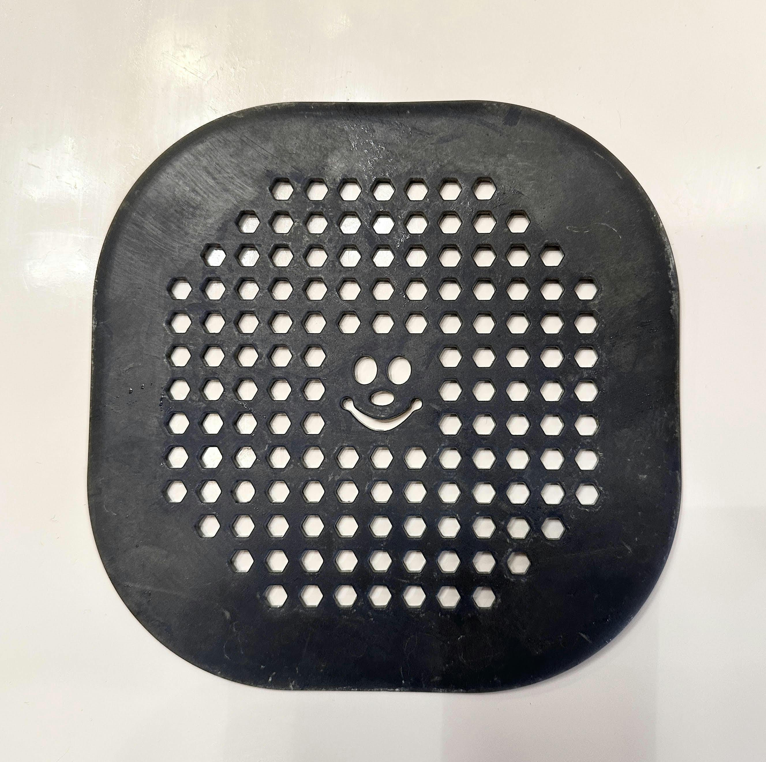 photo of a drain cover whose central holes make a happy face