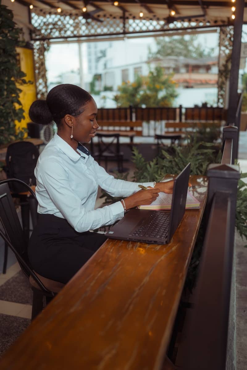 Woman working on a laptop at an outdoor cafe.