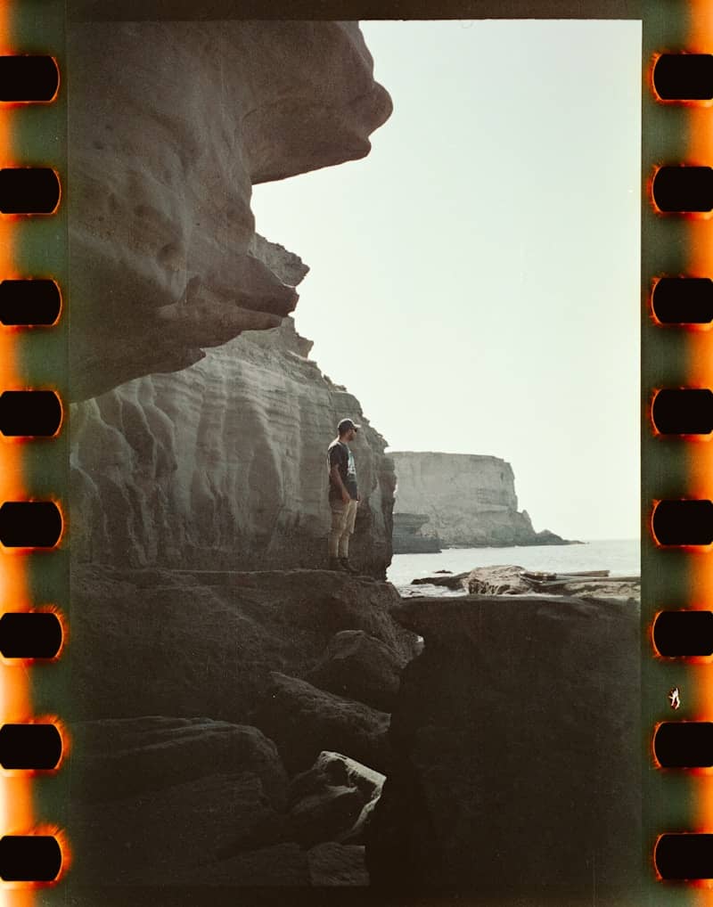 A man standing on top of a cliff next to the ocean