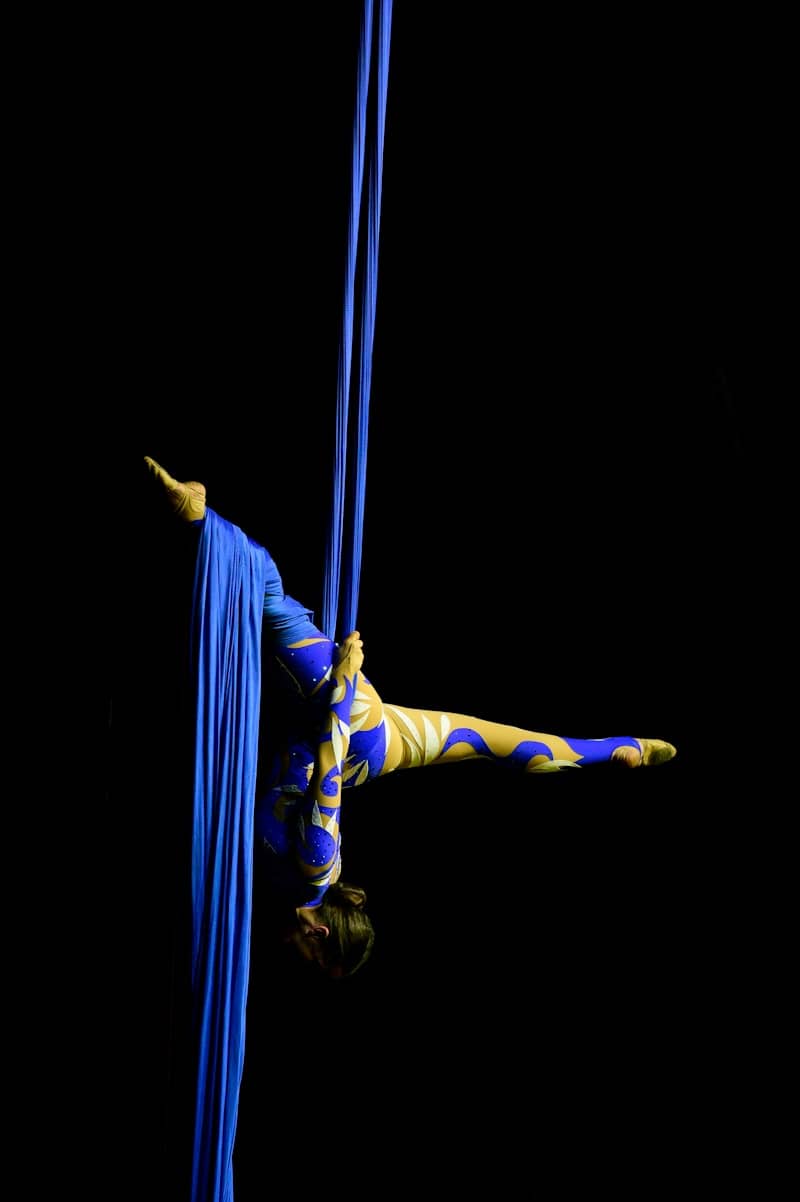 A woman is doing aerial acrobatic tricks on a pole