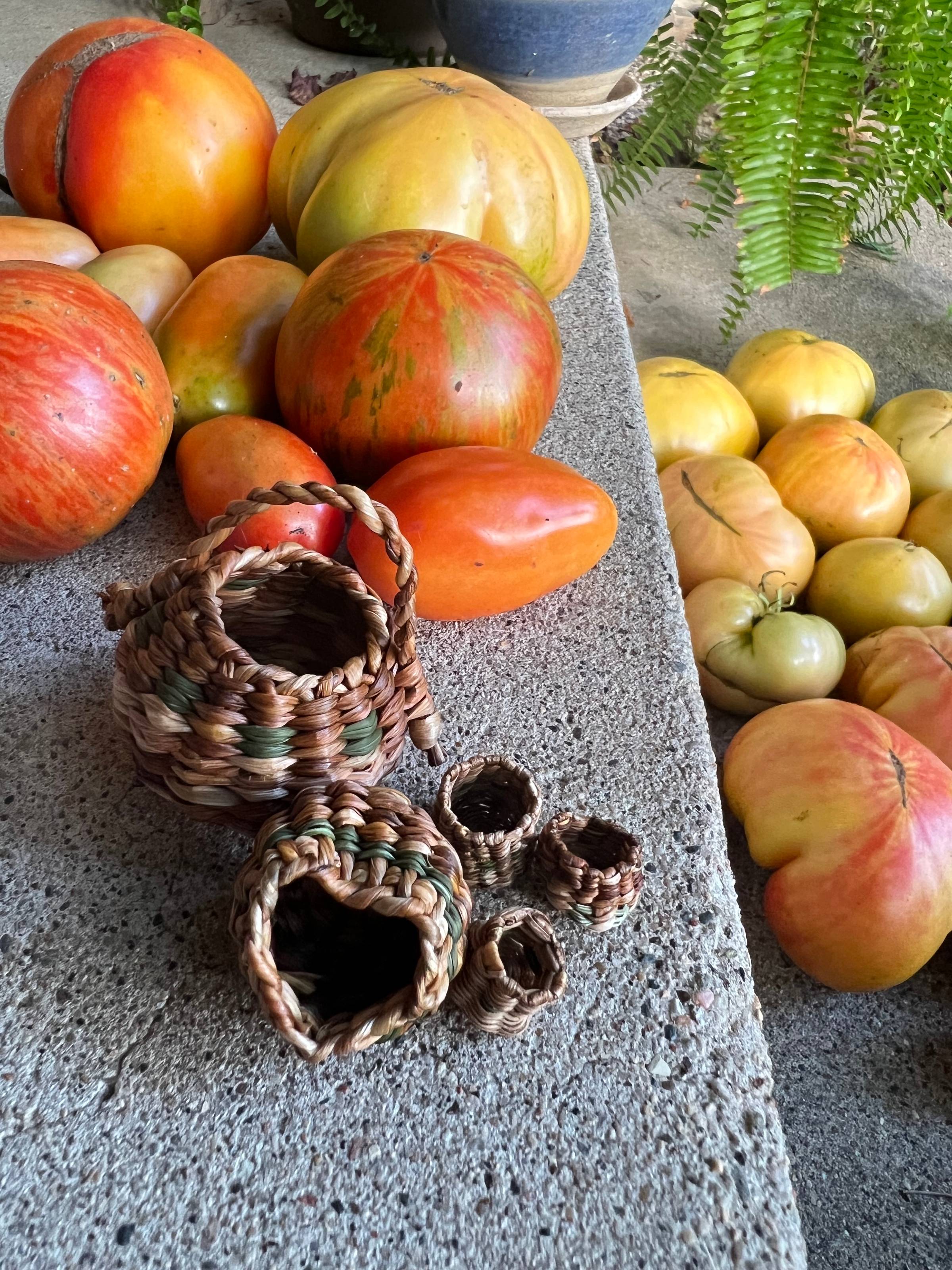 five tiny baskets on the front porch next to an abundance of tomatoes
