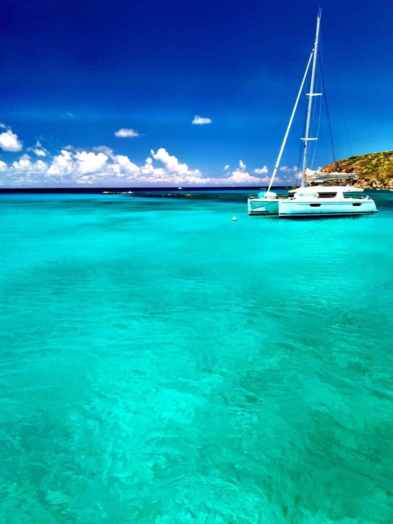 white and blue sailboat on sea under blue sky during daytime