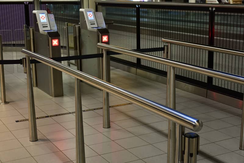 Metal turnstiles and railings at a transit station.