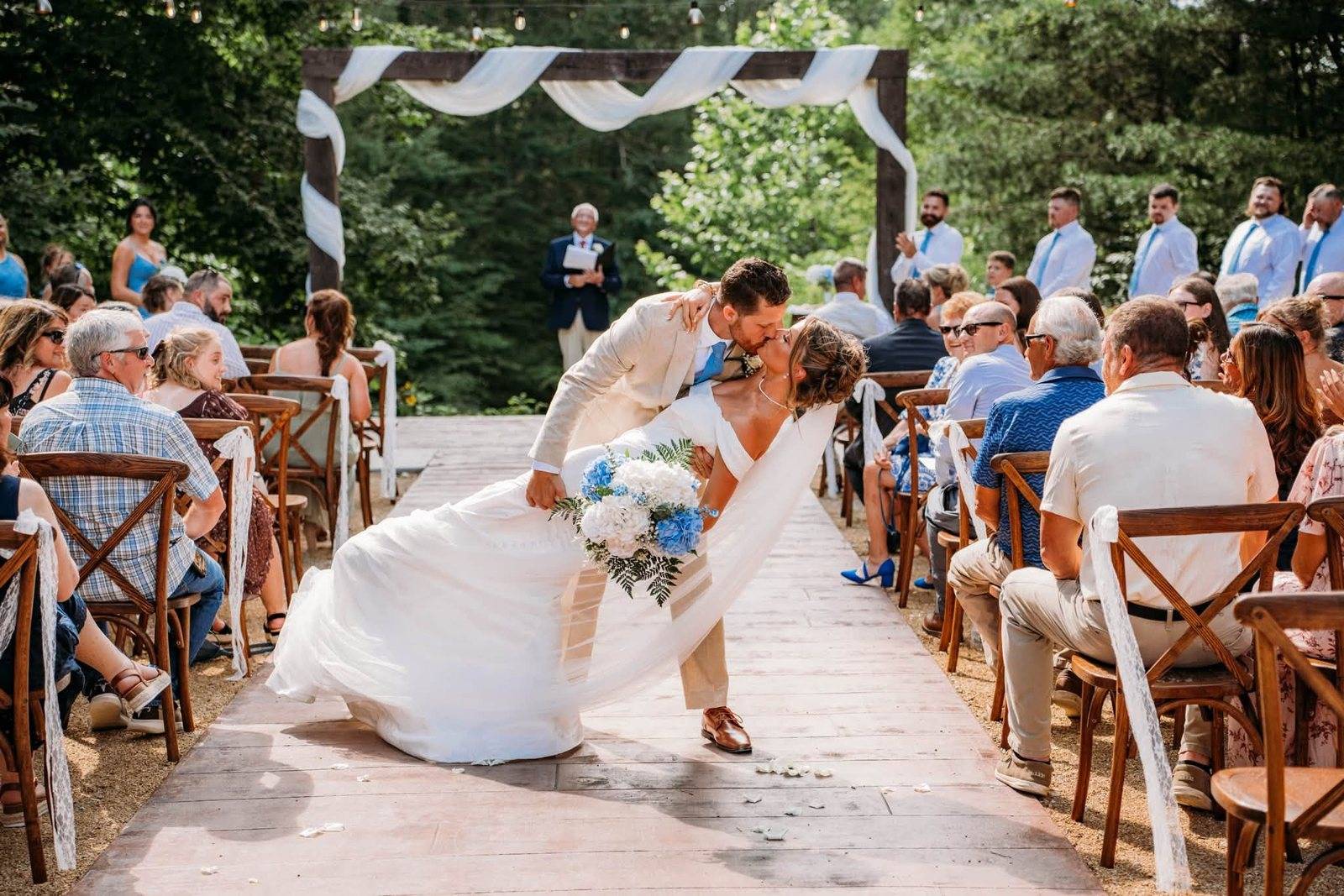 Groom dips the bride for a kiss as guests cheer at The Reflection