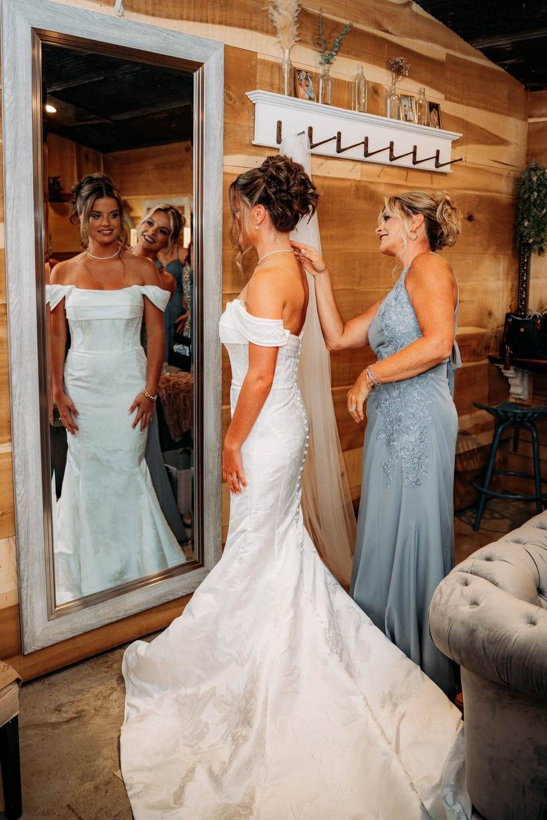 A mother helps the bride with her gown in the Timber Ridge bridal suite