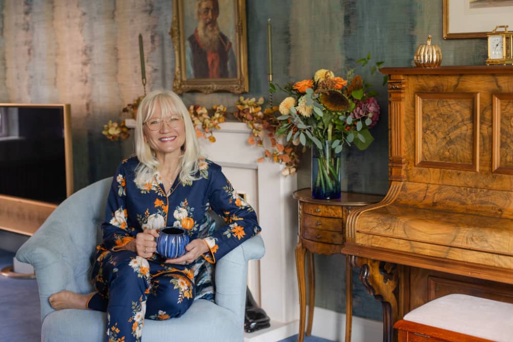 April Harris wearing pumpkin pyjamas sitting in an armchair holding a blue pumpkin coffee mug