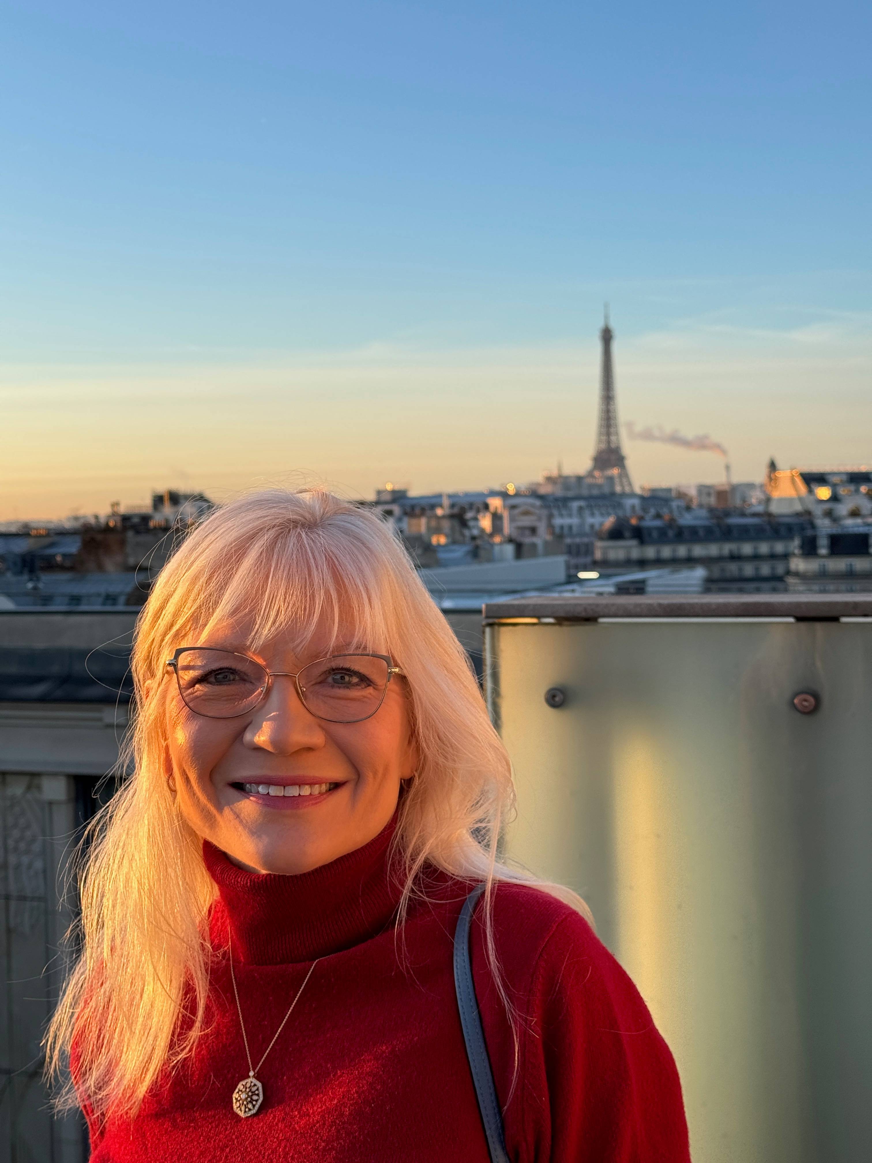 April Harris on the balcony of a Paris hotel with the Eiffel Tower in the background.