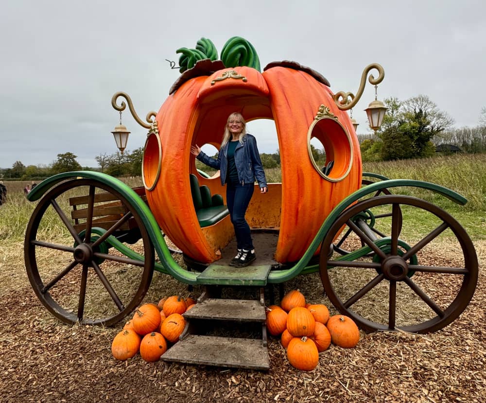 April J Harris standing in a pumpkin coach in a pumpkin patch