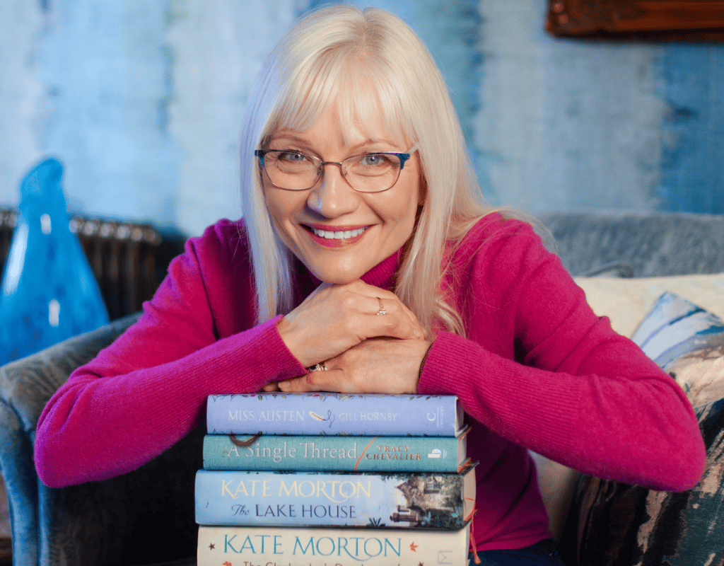 April Harris resting her hands on a pile of four books