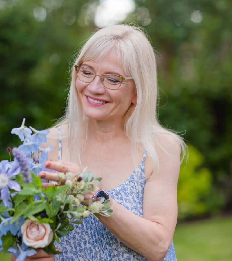 April Harris in a garden looking down at a bouquet of flowers in her hand