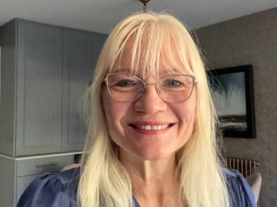 April Harris photographed in her kitchen. There is a blue cabinet behind her on the left and a painting behind her on the right. 