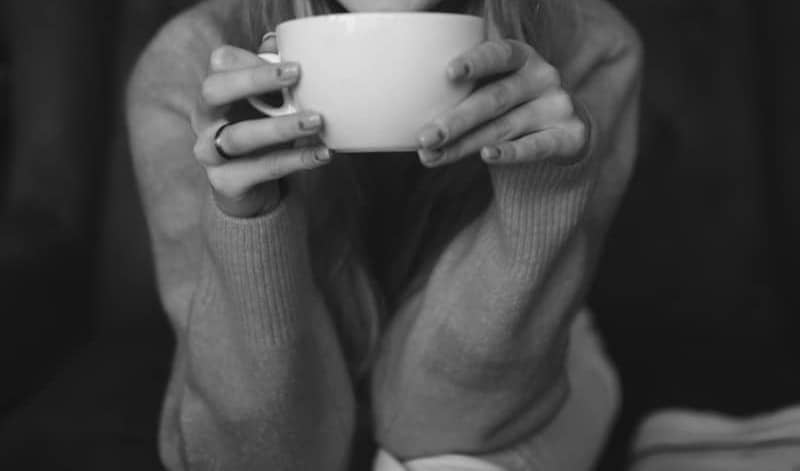 Smiling woman in beanie holding a cup.