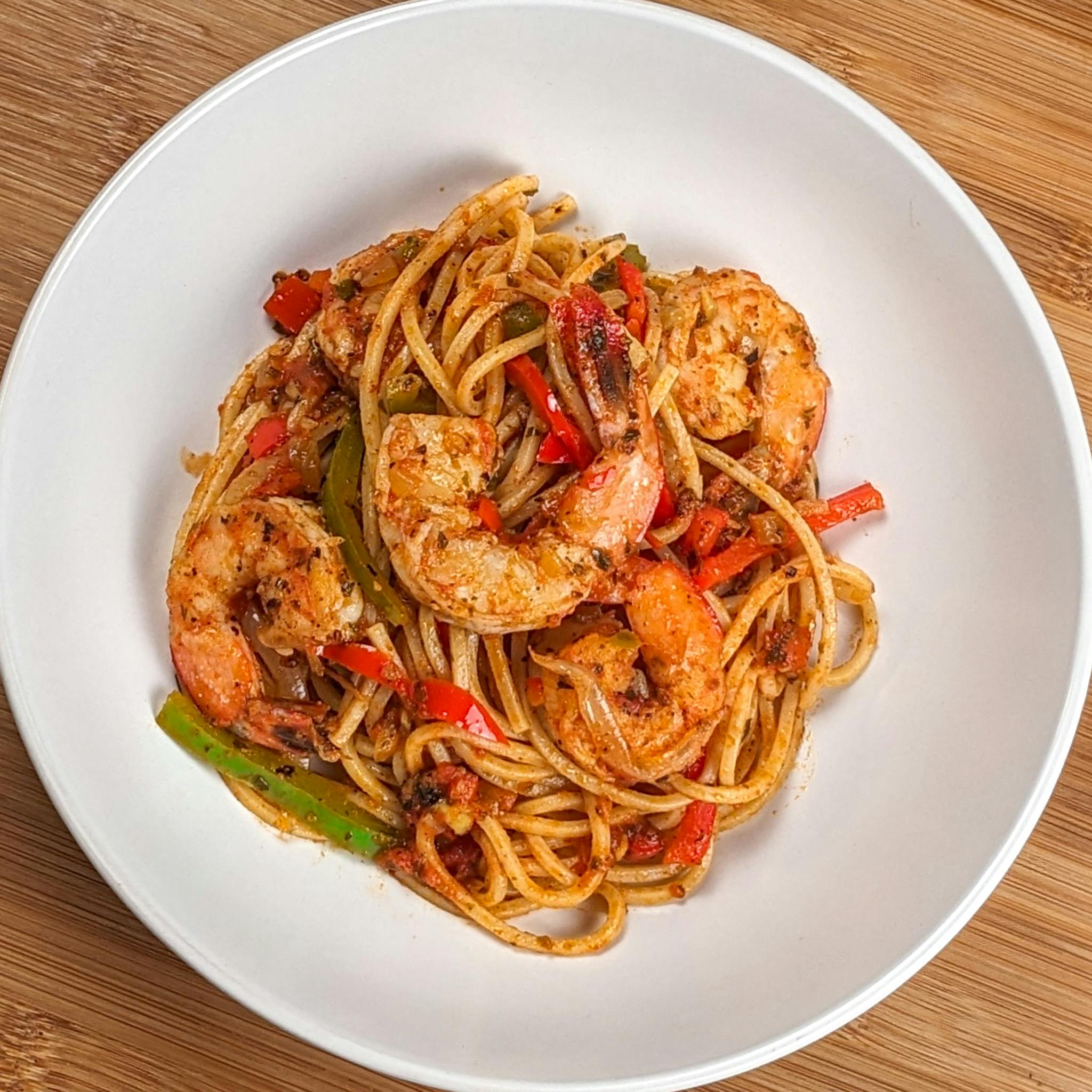 Close-up of the Haitian-style spaghetti with shrimp and creole sauce in a wide-rim pasta bowl.