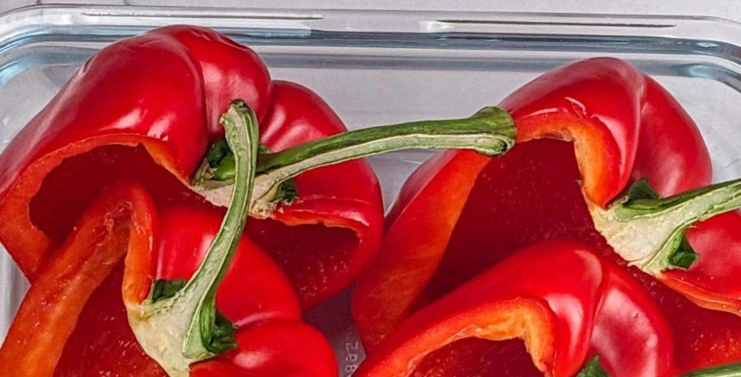 halved red bell peppers in a glass container.