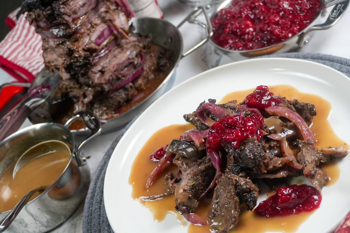 plated steak shawarma with gravy and cranberry chutney surrounded by the finished dishes.