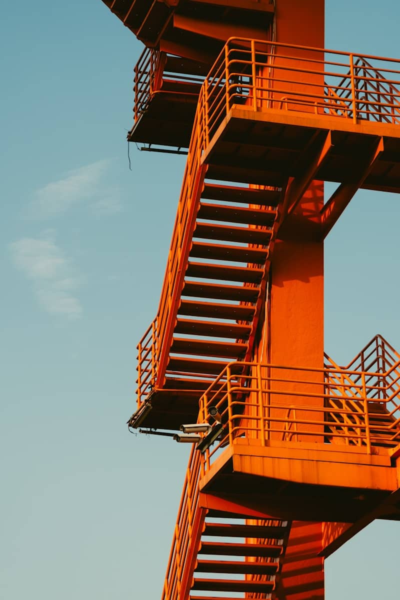 Orange stairs ascend against a blue sky.