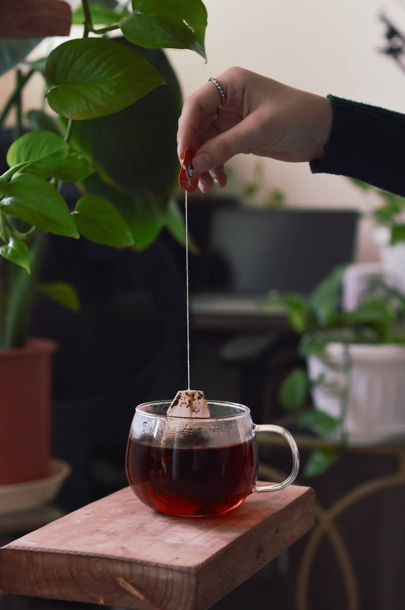 A person holding a spoon over a cup of tea