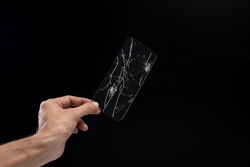 A hand holding up a broken cell phone