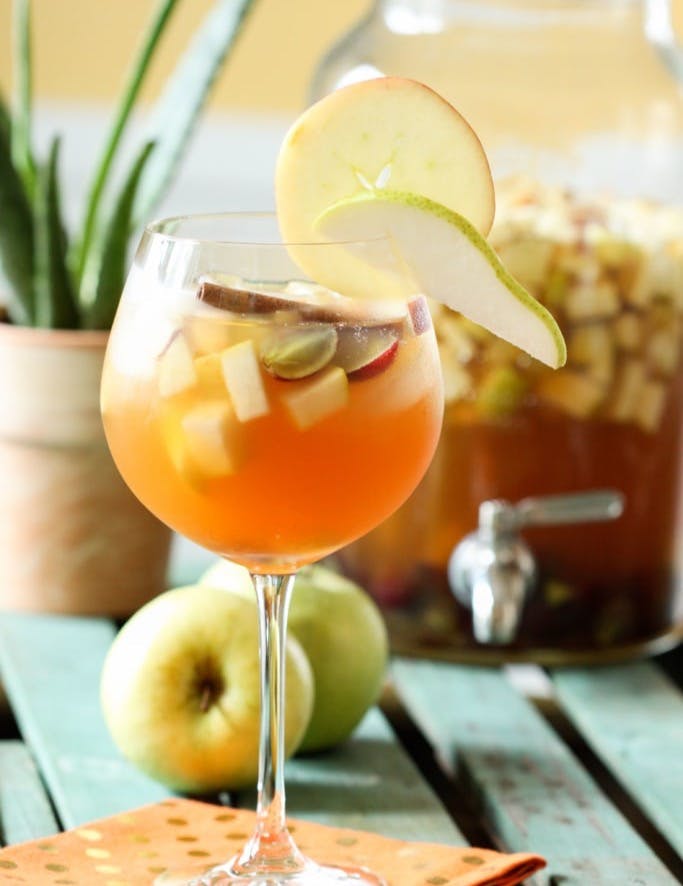 Apple Cider Sangria served in a large wine glass with cut fruit.