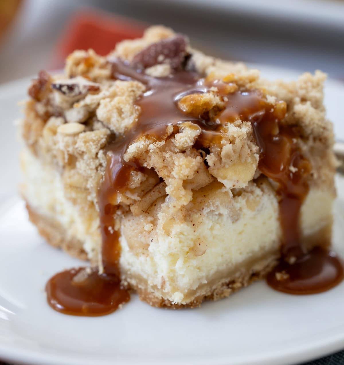 piece of Salted Caramel Apple Cheesecake on a plate with caramel sauce.