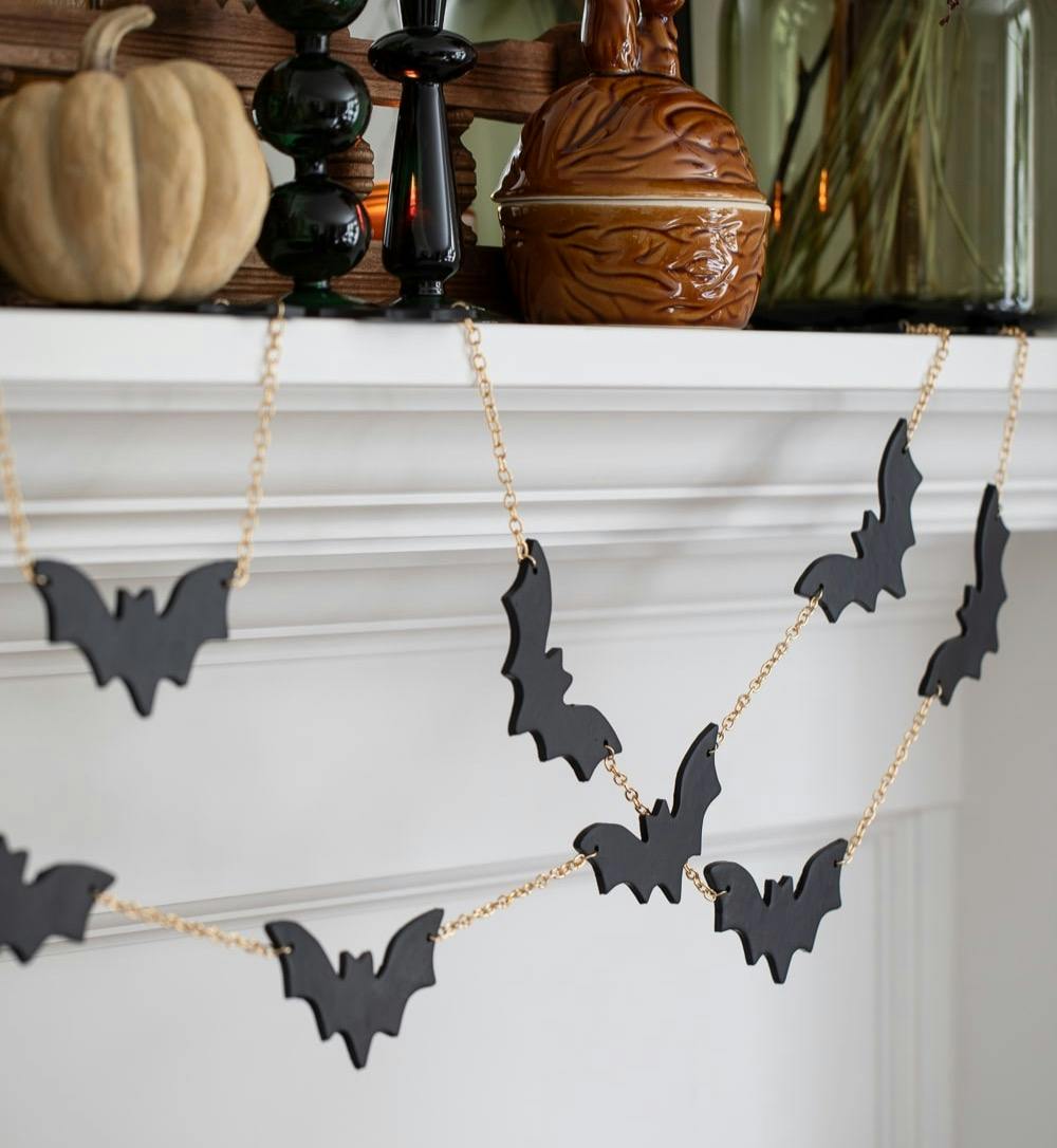 diy bat garland with black bats and gold chain on a white mantel.