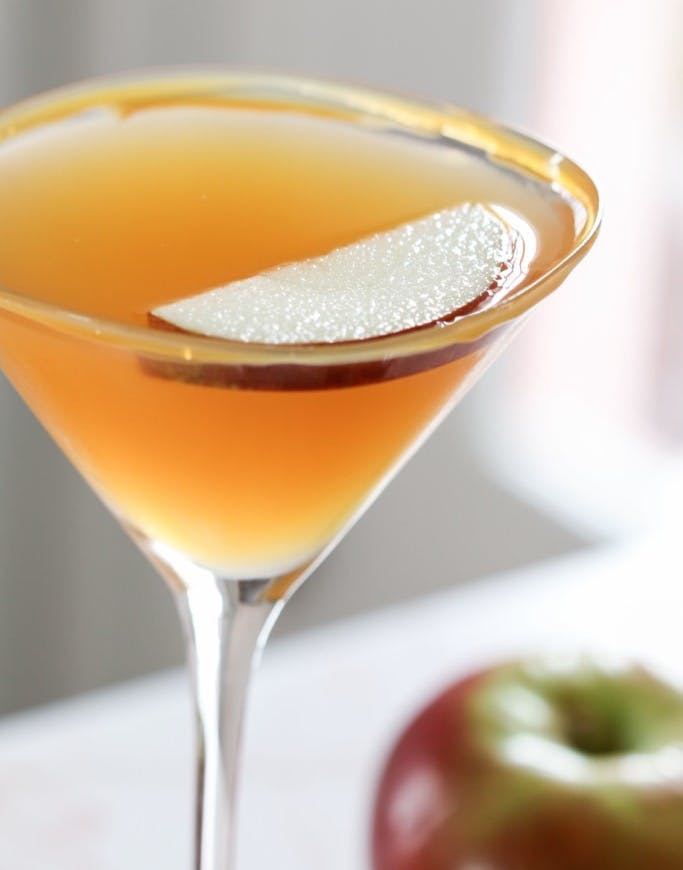 caramel apple martini with apple slice garnish in martini glass.