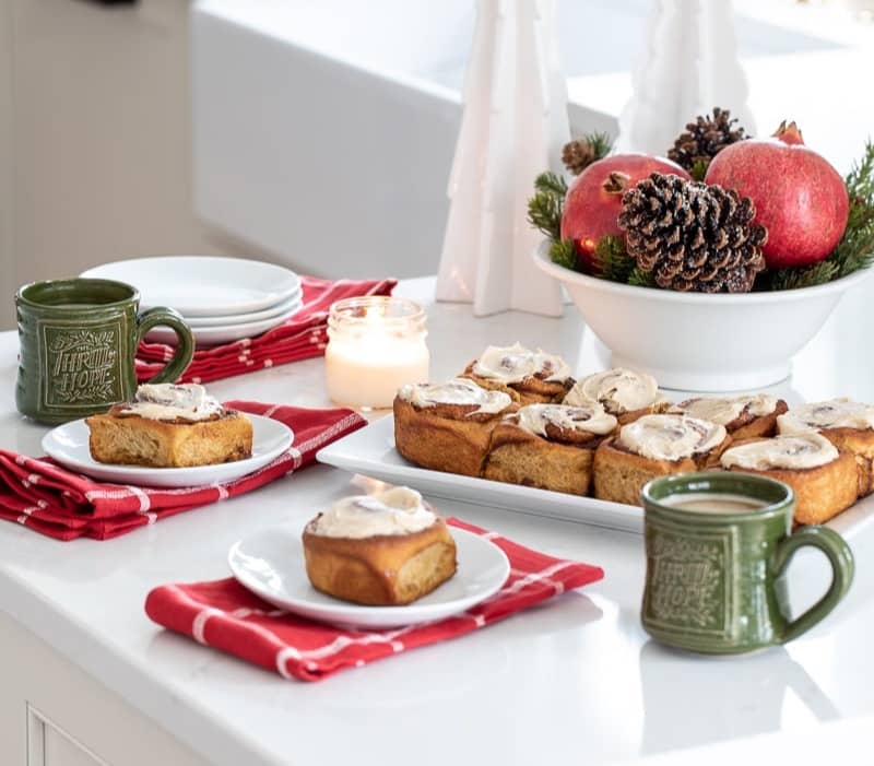 Gingerbread Cinnamon Rolls served in a kitchen with coffee and holiday decor.
