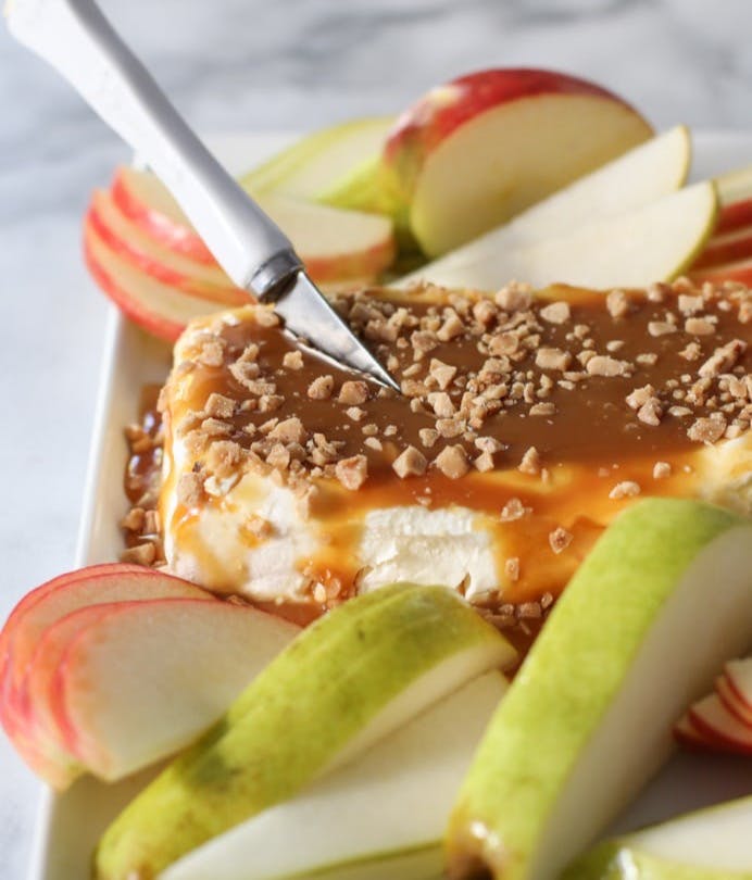 cream cheese caramel apple spread served on a plate with fresh apple slices. 