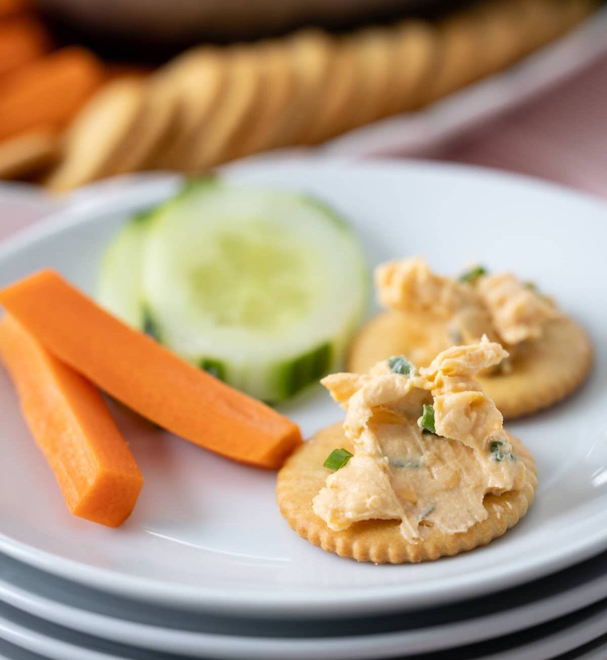 small plates stacked together with cheese on crackers and veggies.