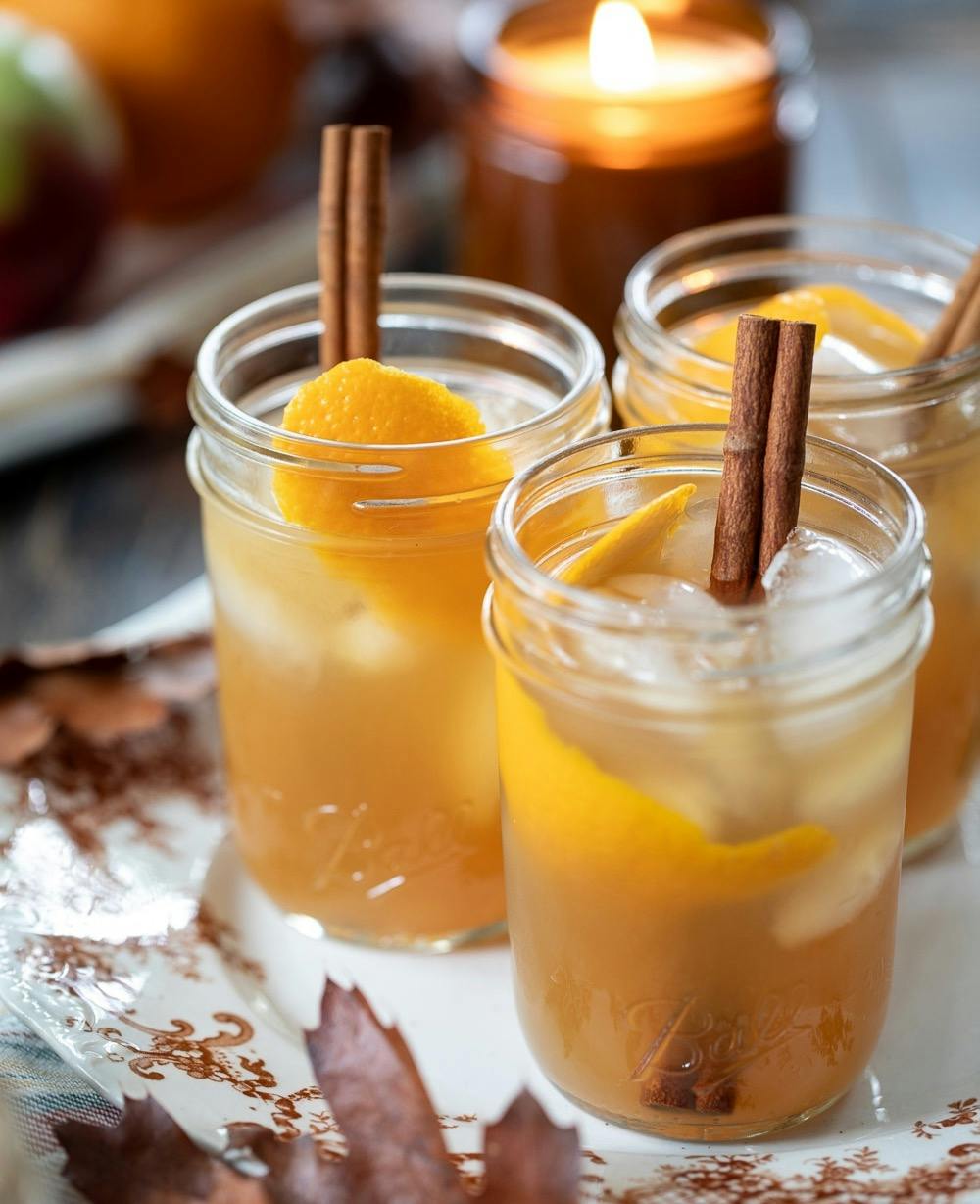 apple cider whiskey sour cocktails served in jars on a plate.