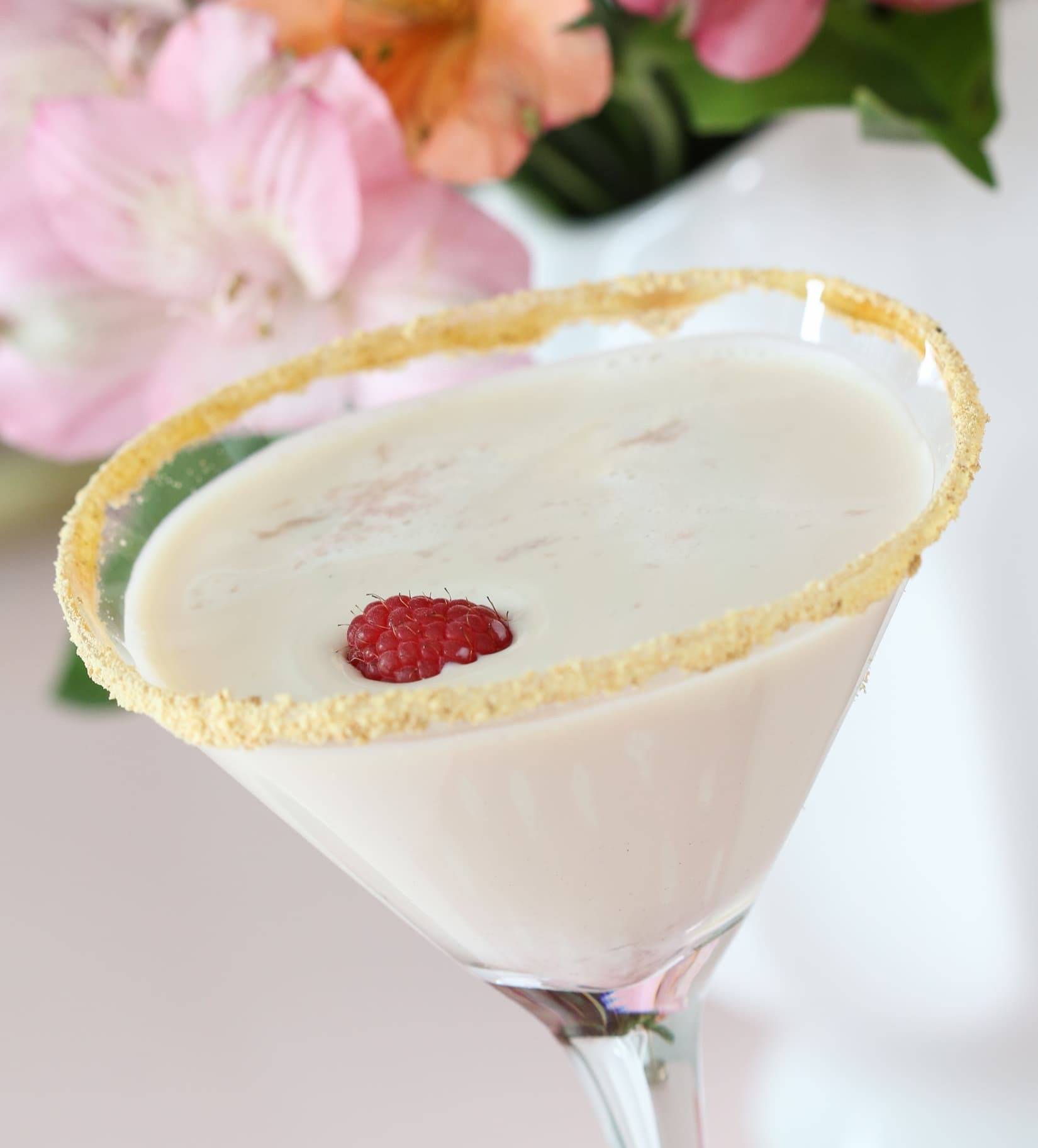 Raspberry Cheesecake Martini in a martini glass with raspberry garnish.