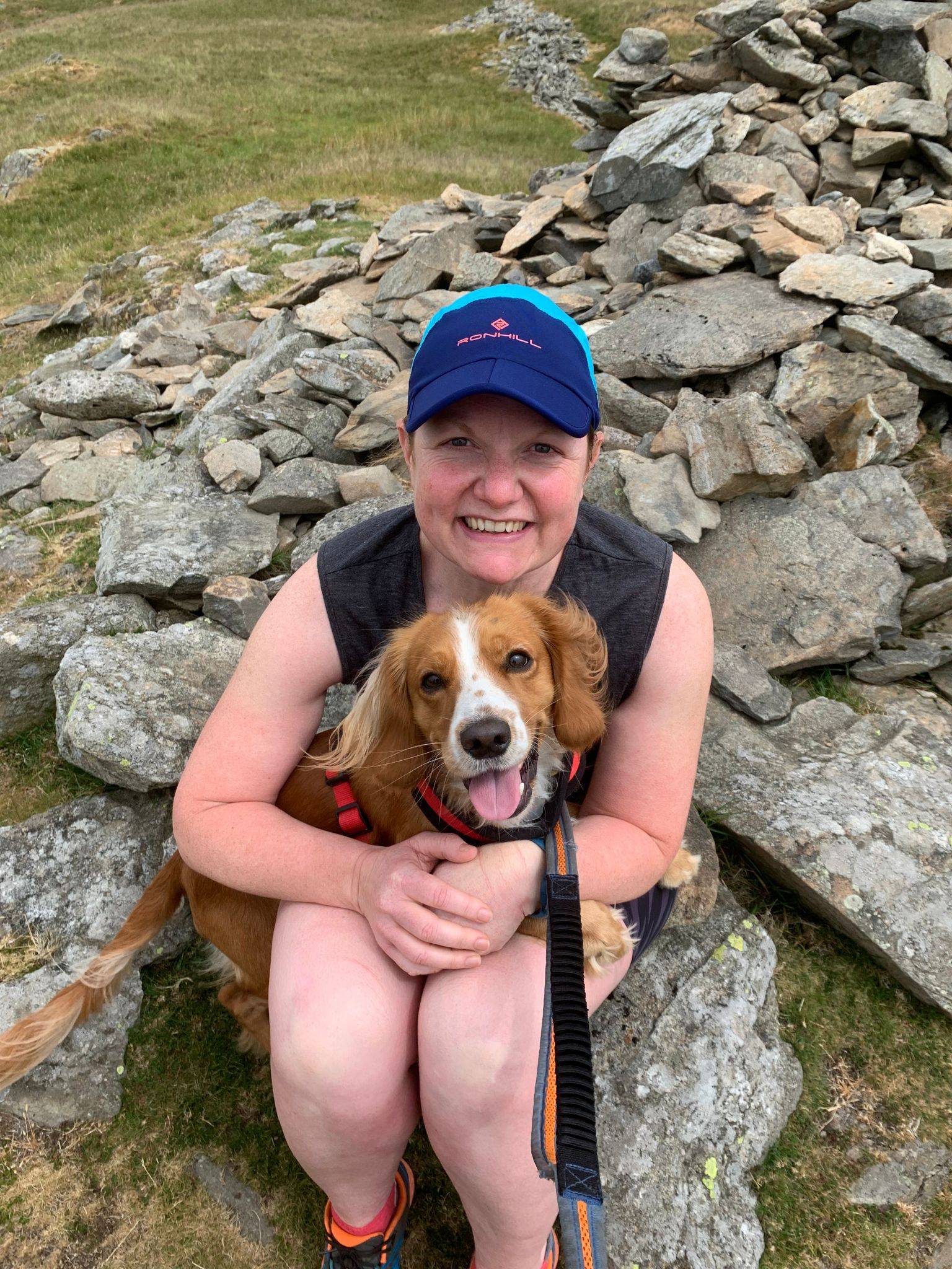 Image of Sheela Hobden with her dog sitting on a mountain in Cumbria, UK.  www.bluegreencoaching.com