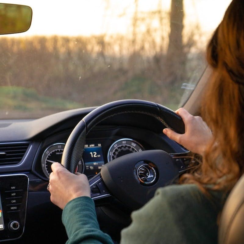 a woman driving a car while holding the steering wheel