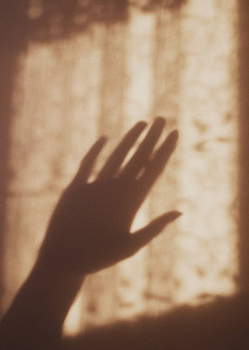 A hand's shadow plays against the light.
