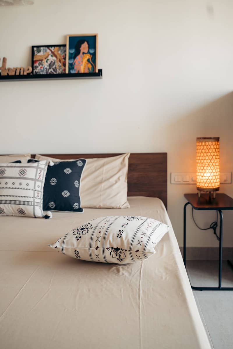 A cozy bedroom with decorative pillows and lamp.