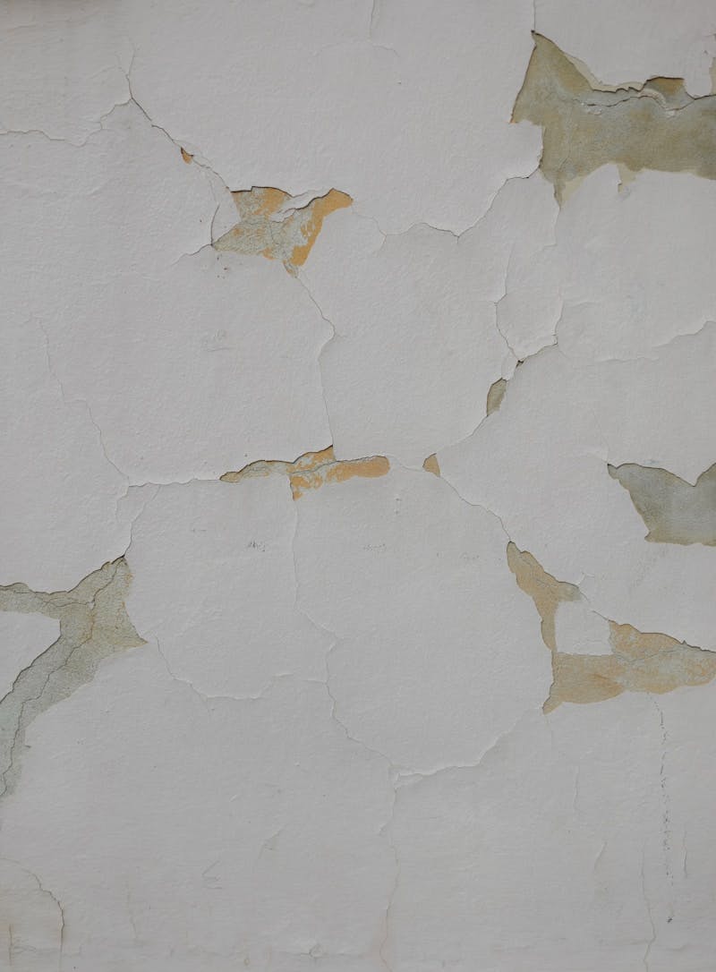 A white wall with peeling paint on it