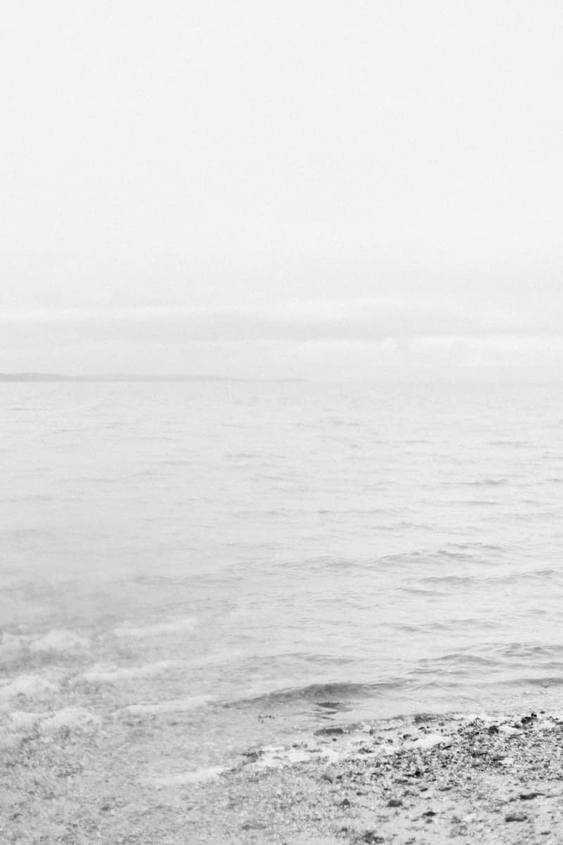 A man standing on a beach holding a surfboard