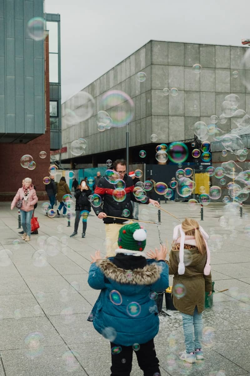 Man blowing bubbles for children outdoors