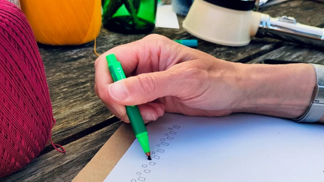 my hand holding a green marker and busy creating a weaving pattern.